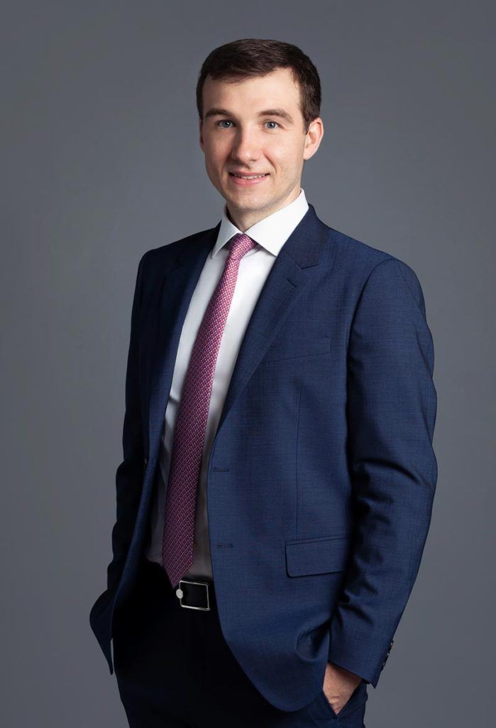man wearing navy suit and pink tie with short brown hair
